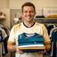 Diy Astor, school team organiser, holding a folded set of custom football shirts